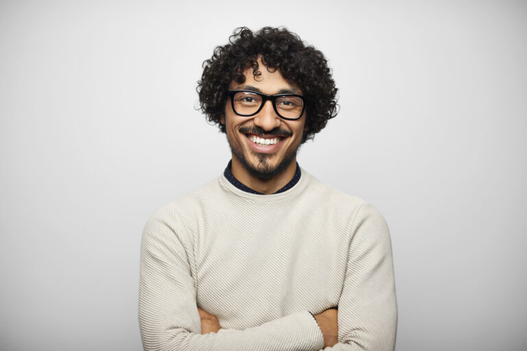 Portrait of smiling Latin American man. Happy young male is wearing eyeglasses and casual. He is against white background.